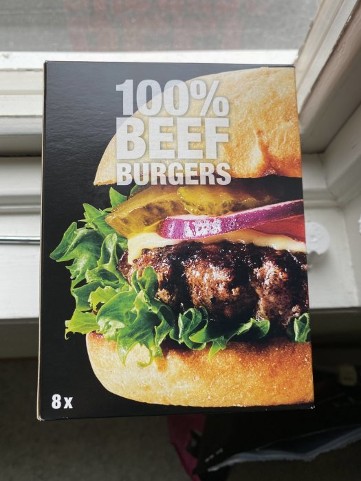 Produktförpackning för 8 stycken 100% nötköttsburgare, innehåller bild av saftig burger med sallad och bröd.