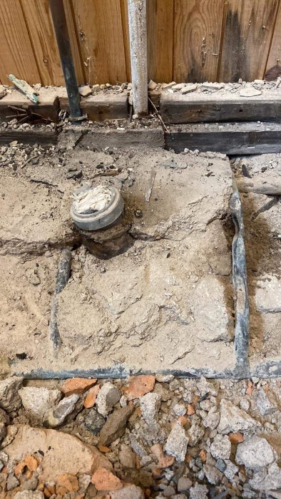 Renovering eller rörmokararbete, synliga rör och kablar, uppbruten golv yta, inomhuskonstruktion, trävägg, betong, grus.