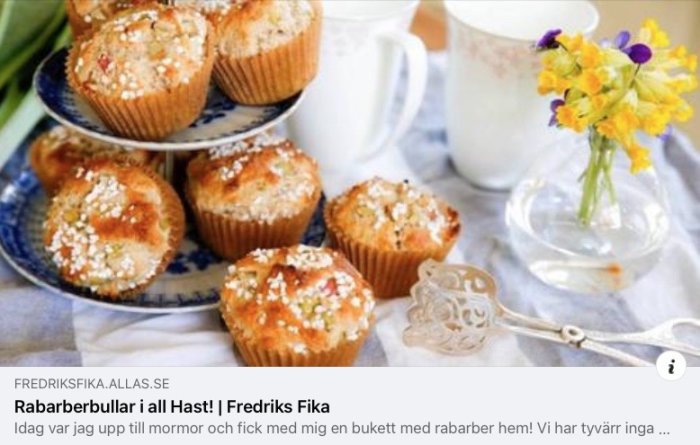 Muffins på blåmönstrad tallrik, blommor i vas, tekopp, ljus bakgrund, hemtrevlig fikastämning.
