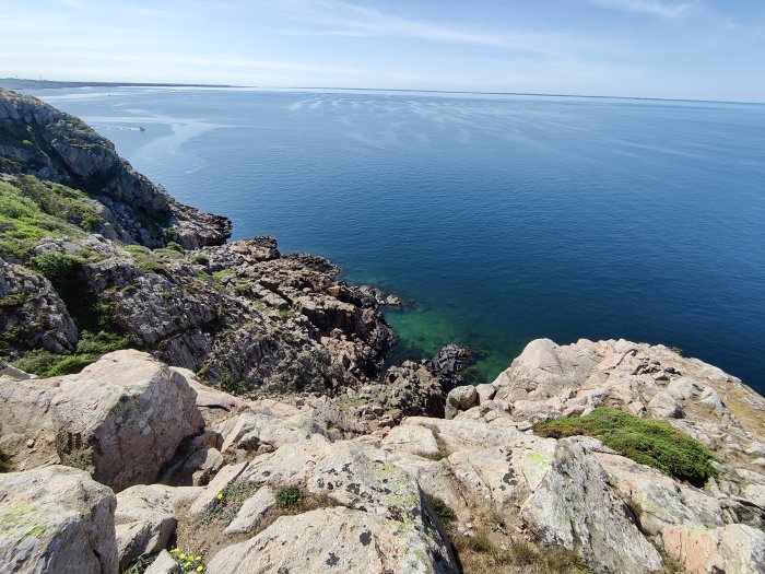 Klippigt kustlandskap, turkost hav, blå himmel, naturskönt, utsiktspunkt, ingen synlig bebyggelse.