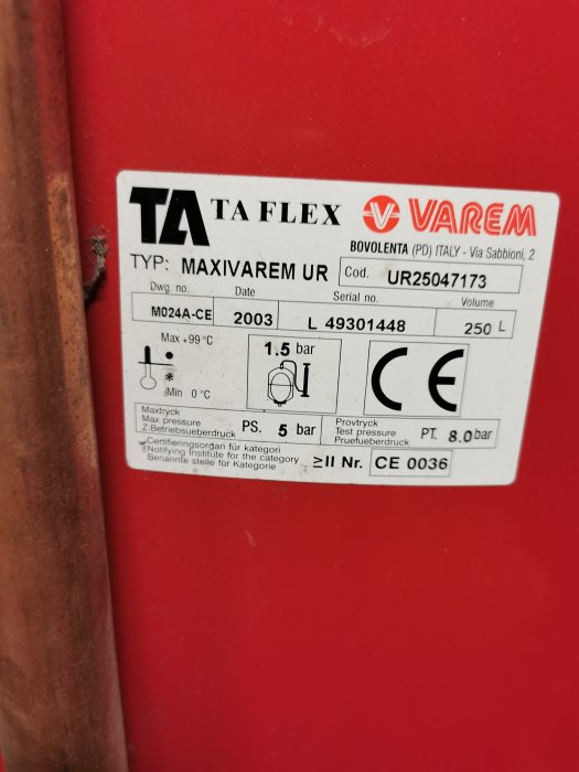 Etikett på röd yta: "TA Flex", "Varem", produktinformation, tryckdata, CE-märkning, tillverkningsår 2003, volym 250 liter.