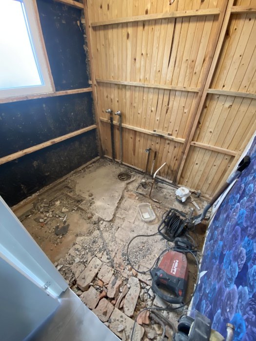 Renoveringsprojekt, demolering av badrum, träpanel, tegelstenar, rörledningar, rörstumpar, dammsugare, byggavfall.