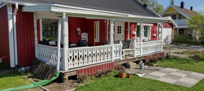 Röd stuga, vit veranda, grönska, grill, soligt, trägång, utemöbler, hemtrevlig, landsbygd, traditionellt svenskt hus.