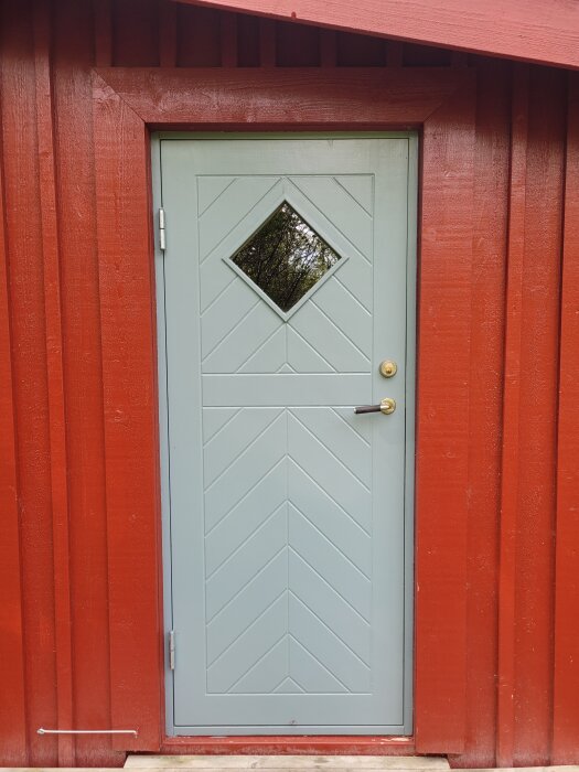 Ljusblå dörr med diamantfönster, karm i rött trähus, traditionell, enkel stil.