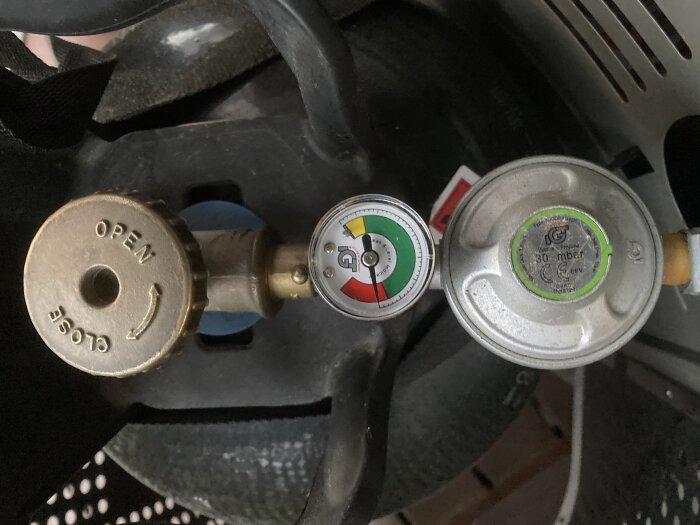 Gasflaskans ventiler och manometrar syns, vilket indikerar tryck och innehållsnivå.