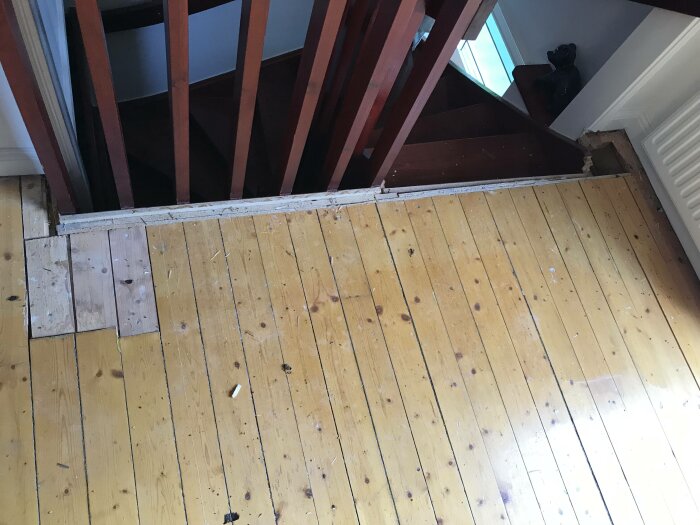 Ett golv vid en trappa under renovering, med synliga reglar och spillror.