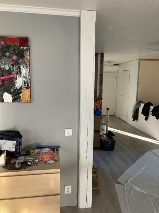 Inomhusmiljö under renovering, pelare, målning på vägg, rörigt, byggmaterial och ommålade element syns.