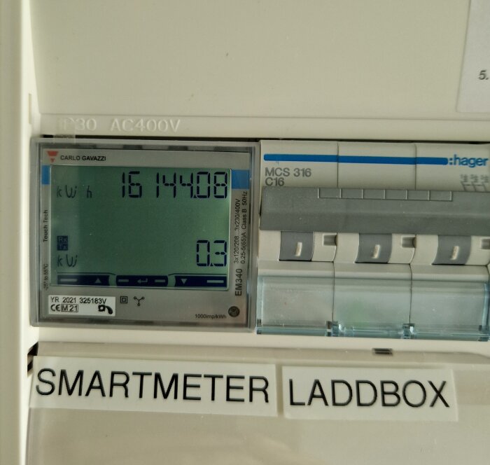 Digital strömmätare med display, energiförbrukning i kWh, märke Carlo Gavazzi, säkringar, text "SMARTMETER LADDBOX".