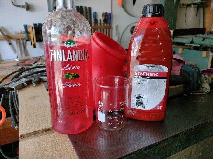 Finlandia Lime vodka, syntetisk motorcykelolja, mätglas, verkstadsbakgrund med verktyg.