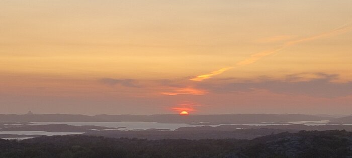 Skymning med solnedgång över hav och skärgård, stämningsfull himmel i apelsin och rosa toner.