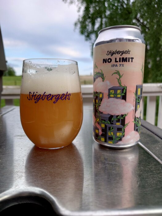 Ölglas märkt "Stigbergets" med skum, IPA-öldryck, "No Limit", utomhus, grönska, balkongvy.