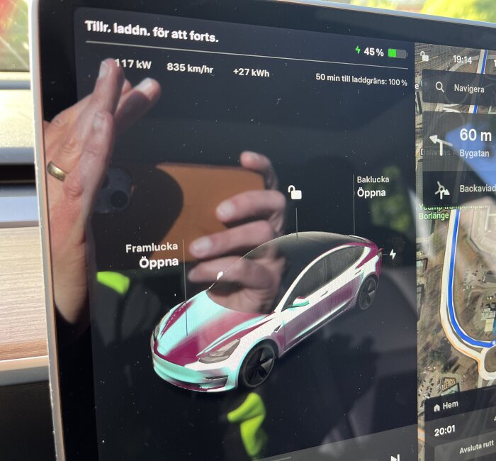 En person interagerar med en elbils infotainmentsystem som visar laddningsstatus och navigation. Reflektioner syns på skärmen.
