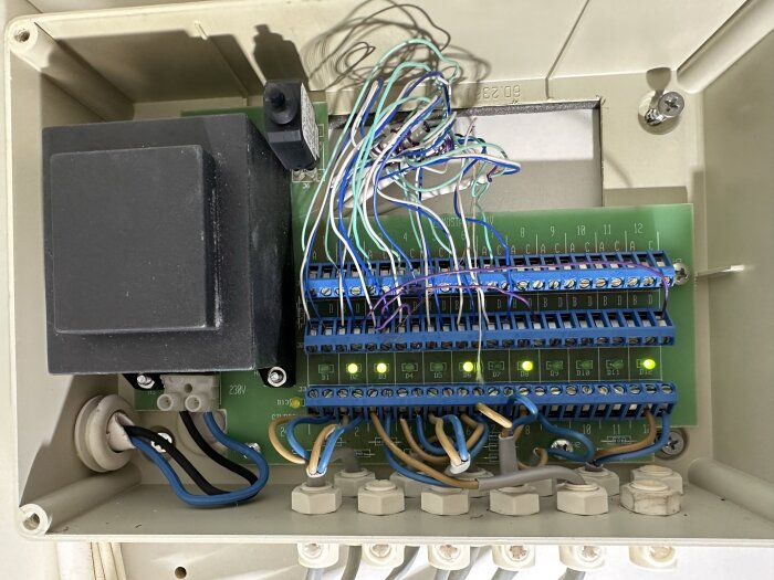 Elektriskt kopplingskåp med kablar, terminaler, transformator och säkringar.