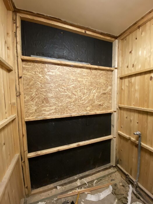 Ombyggnadsarbete, träpanelväggar, isoleringsskivor, byggnadsmaterial, under konstruktion, rör på golvet.