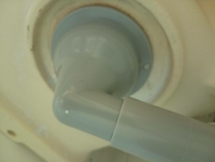 Närbild, otydlig, blå plastdel, kopplad till vit maskin eller apparat, grumligt, bruksspår, svagt ljus, suddig.