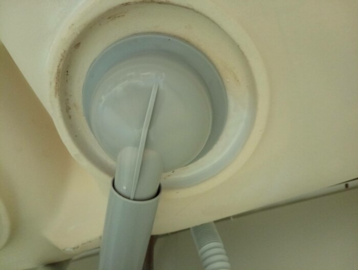 Närbild av tandläkarutrustning, sugslang och ljuset, mot en ljus bakgrund, lite smuts och missfärgningar syns.