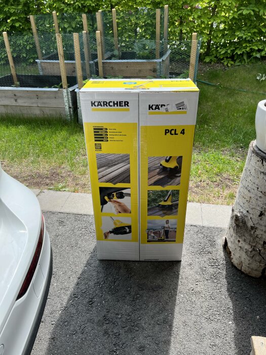 Förpackning för Kärcher PCL 4 terrassrengörare utomhus nära bil och träbit, på en solig dag.