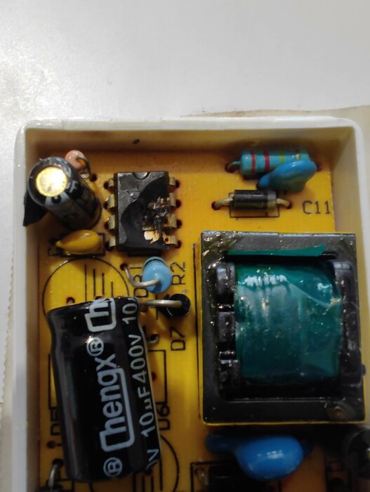 Elektronikkort med kondensatorer, motstånd, integrerad krets och anslutningar, delvis i omslag.