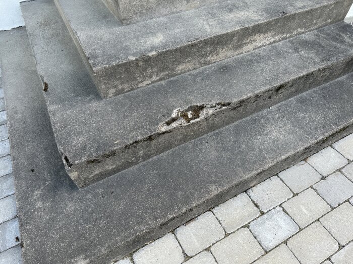 Slidt betontrappe med beskadigede kanter, revner og huller, der tydeligt viser behov for renovering og reparation.