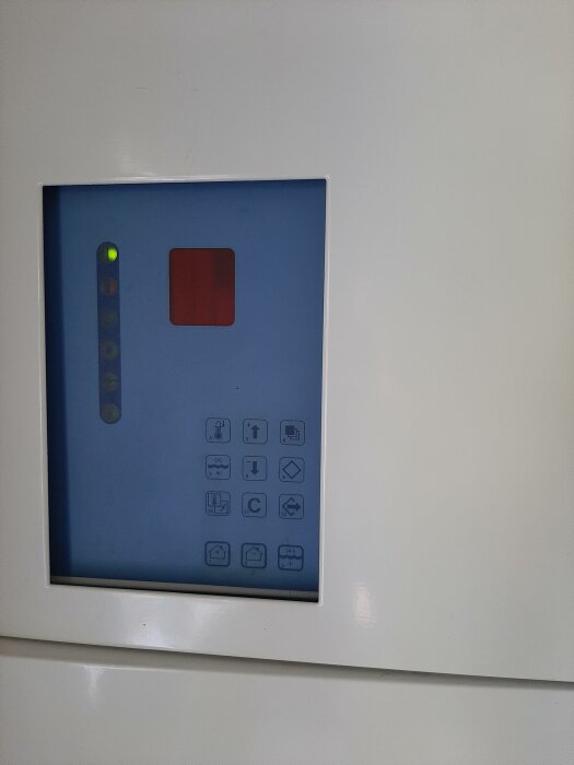En hisspanel med knappar och ljusindikatorer, modern design, inbäddat i vit vägg.