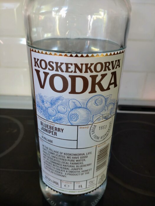 Flaska Koskenkorva Vodka, Blåbär Enbär smak, infon om produkt och ursprung. Transparent vätska, alkoholhalt noterad.