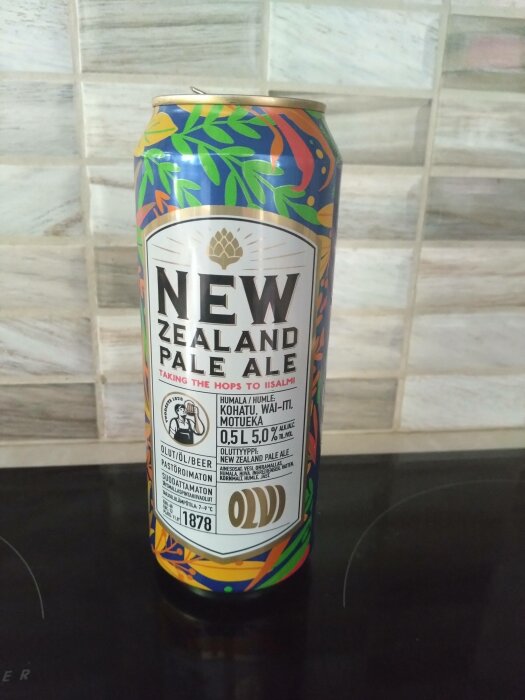 Burk "New Zealand Pale Ale", färgglad design, alkoholhaltiga dryckesinformation, mot kakelvägg.