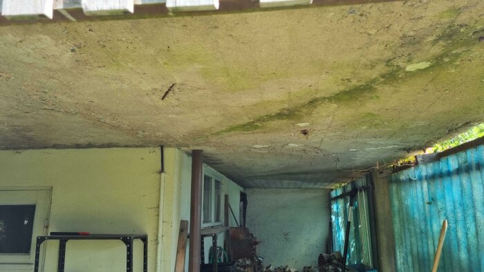 Försummad utrymme under betongtak: mögel, förfall, oönskad prylar, övergivna möbler, fönster, murken infrastruktur.