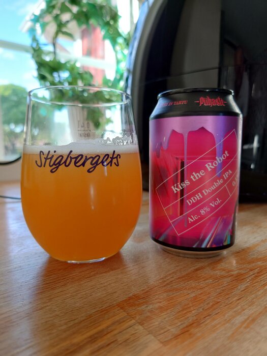 Ett glas öl, ölburk "Kiss the Robot" DDH double IPA, träbord, inomhusmiljö, fönsterutsikt med grönska.