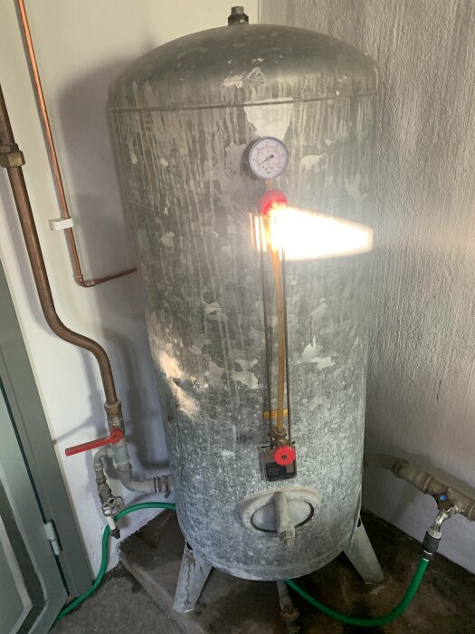 Expansionskärl för värmesystem med manometer, rörkopplingar och säkerhetsventil i ett tekniskt utrymme.