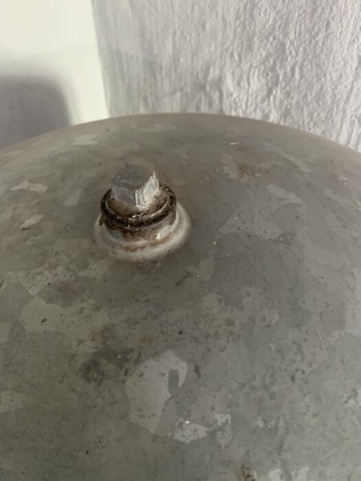 Grå metallobjekt, rostig bult, textur, närbild, inget sammanhang.