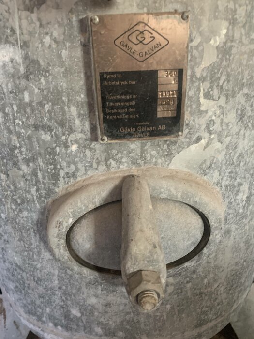 Metallbehållare med märkesplåt och handtag, används antagligen för industriellt eller tekniskt syfte.