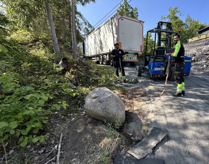 Olycka, lastbil i diket, två personer, gaffeltruck, rep, räddningsarbete, skadat flak, natur, stenar, träd.