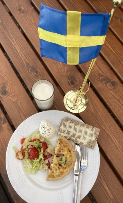 Svensk flagga, frukost, ägg, paj, knäckebröd, sallad, mjölk, träbord utomhus.