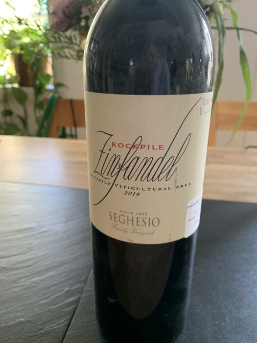 Ett vinflaska med etikett "Rockpile Zinfandel, Seghesio Family Vineyards, 2016" på ett bord.