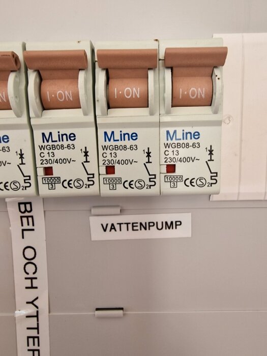 Trebrytarsäkringar i position "på", etiketter för "KABEL OCH YTTERBELYSNING", "VATTENPUMP". Elektrisk säkerhetsutrustning.