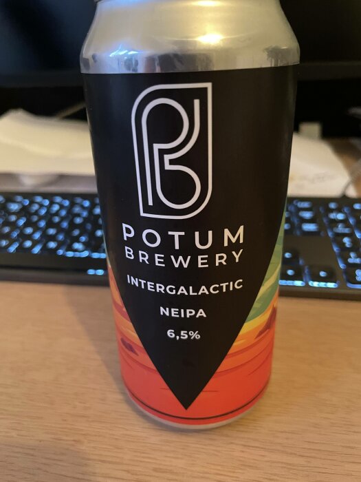 Ölburk, "POTUM BREWERY INTERGALACTIC NEIPA", alkoholhalt 6,5%, färggradient, bord med tangentbord i bakgrunden.