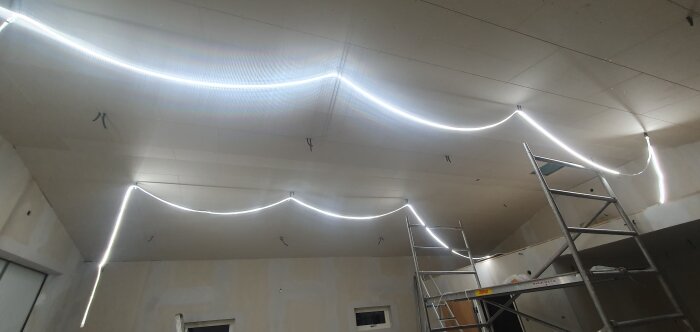 Modern LED-takbelysning under installation i ett rum med stegar och orappat tak.