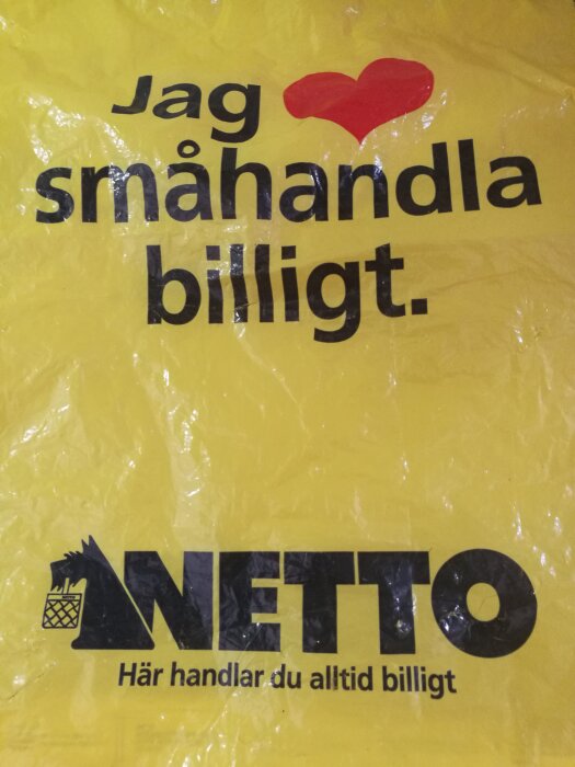 Gul shoppingpåse med text "Jag älskar att småhandla billigt." Logotyp för Netto, slogan nedanför.