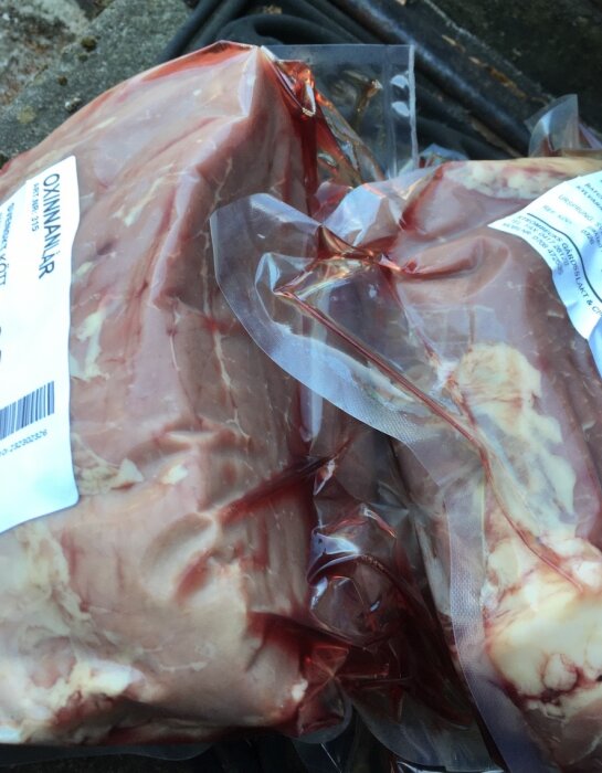 Förpackat, rått kött, märkt med etiketter, sannolikt nötkött, i vakuumförpackning, redo för försäljning eller förvaring.