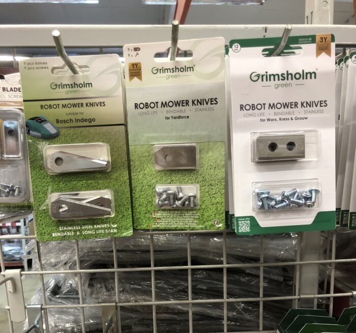 Robotgräsklippare knivar och skruvar på försäljningsförpackningar, märket "Grimsholm Green", i butikshylla.