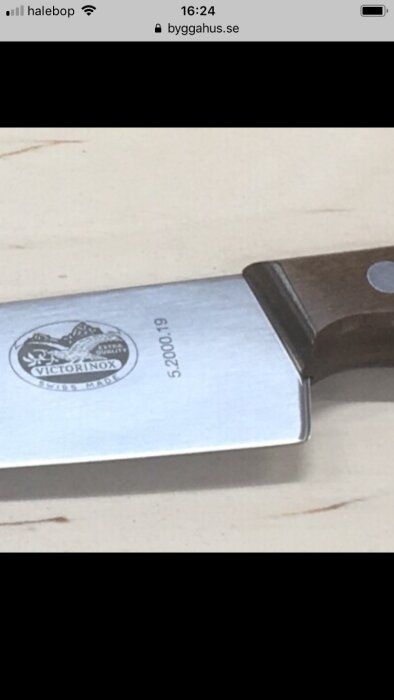 Knivblad närbild, märke synligt, trähandtag delvis synligt, bakgrund suddig, tydlig text "Victorinox Swiss Made".