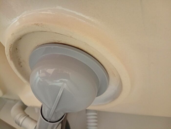 Gråa rör och vitt tak med en spotlight; lite damm och smuts runt armaturen.