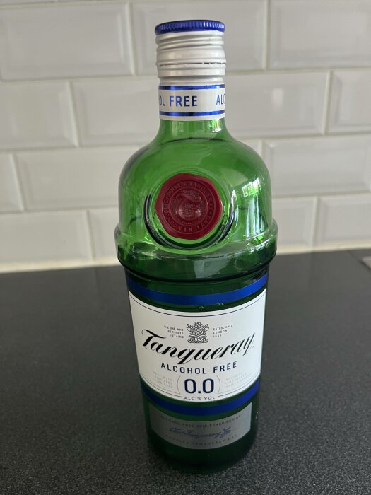 Alkoholfri Tanqueray-flaska, 0.0% vol, etikett, grön flaska, vit bakgrund med metro-kakel.