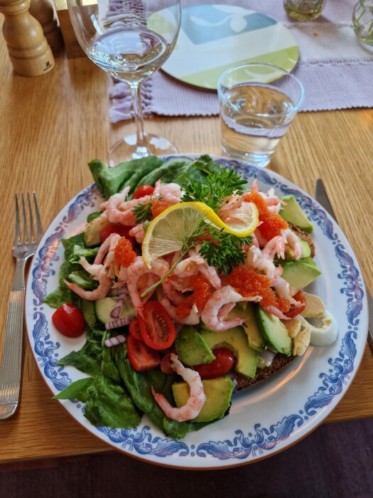 Räkor och avokado på smörgås med sallad, citron, och tomater, serverad på en blommig tallrik, festlig måltid.