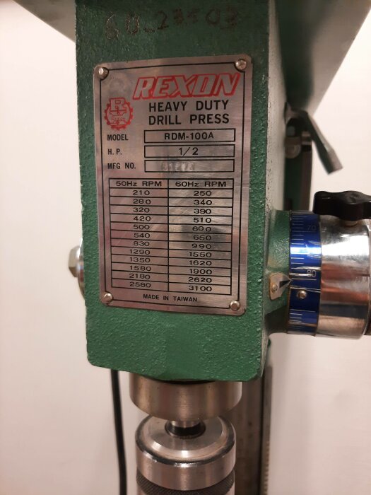 Informationsskylt på en REXON Heavy Duty Drill Press med modellnummer och varvtalsinställningar för olika frekvenser. Made in Taiwan.