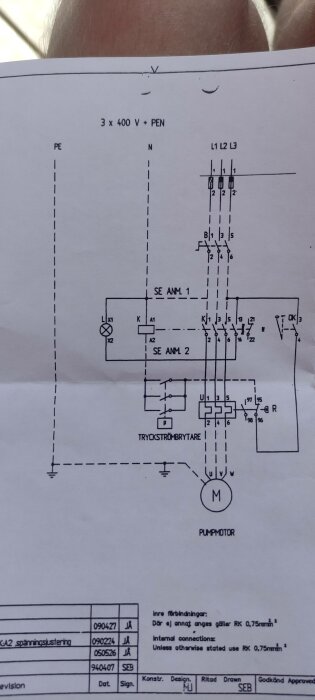 Elritning för styrning av en pumpmotor, innehåller kontaktorer och tryckströmbrytare, på ett papper som hålls.