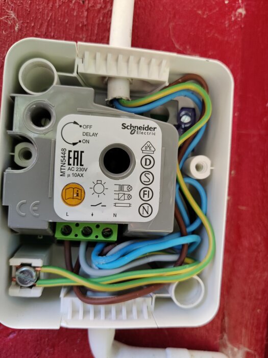 Elektrisk timer i dosa, Schneider Electric, kablar anslutna, röd bakgrund, installationsutrustning, teknisk komponent.
