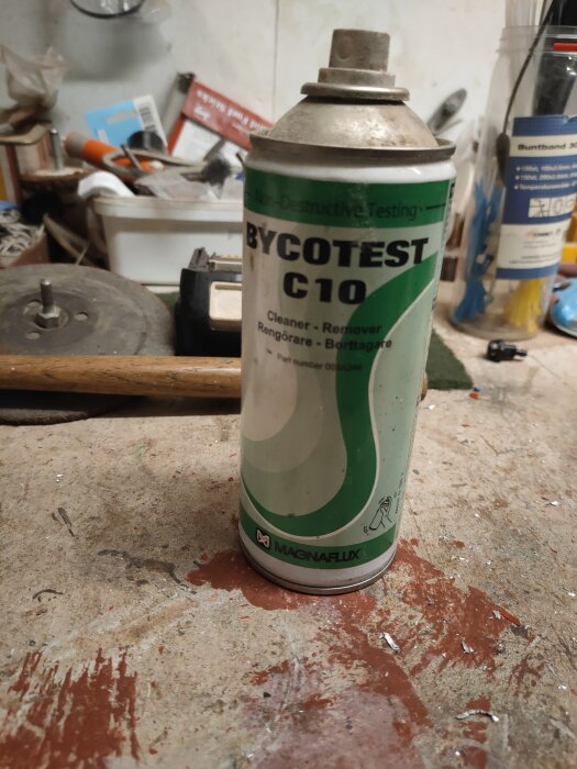 Sprayburk märkt "BYCOTEST C10" på smutsigt arbetsbänk i en rörig verkstad.