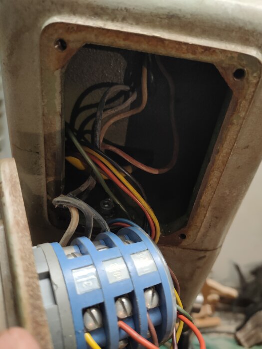 Eldragning inuti en rostig metallstruktur med elektriska komponenter och ledningar synliga.