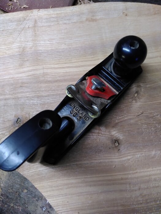 Hyvel på trästycke, metallkonstruktion, svart knopp, märkt "ENGLAND", rött, verktyg för snickeri.